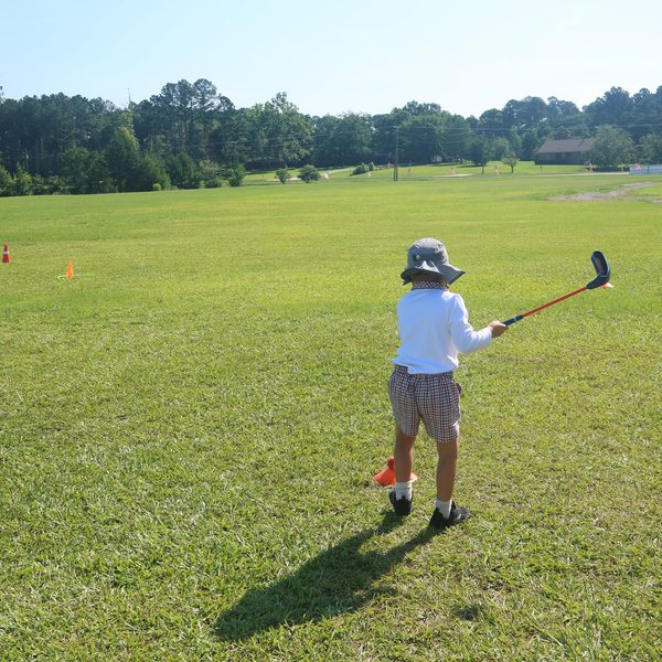 A little golfer takes a full swing on the practice field